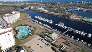 Vue aérienne d’une marina avec des bateaux amarrés, une piscine et des immeubles résidentiels adjacents.