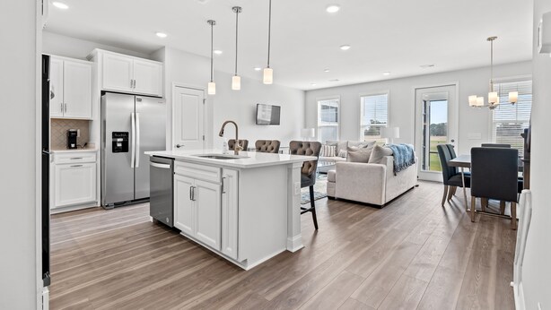 Une cuisine moderne avec des meubles blancs, un îlot central et des luminaires suspendus.