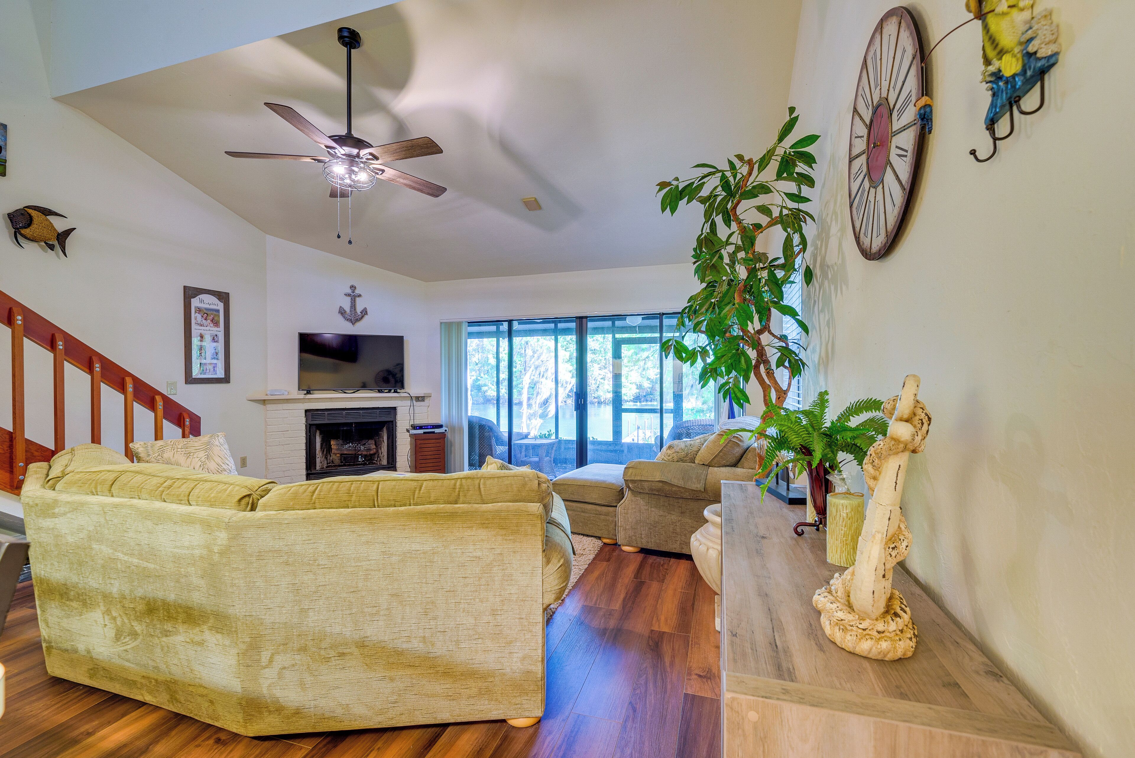 A living room with a sofa, a coffee table, a fireplace, and a ceiling fan.