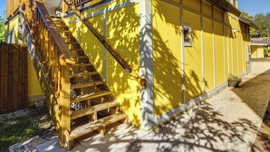 Ein gelbes Gebäude mit einer Holztreppe, die zu einem Balkon führt.