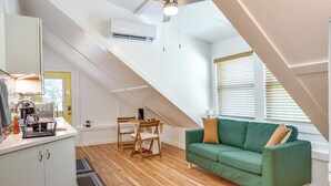 Ein Loft-Zimmer mit grünem Sofa, Holzboden und einem Essbereich mit Tisch und Stühlen.