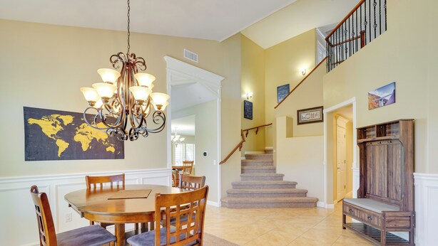 A dining area with a wooden table and chairs, a chandelier, and a world map on the wall. - Corona De Tucson Home With Hot Tub! (Vail)