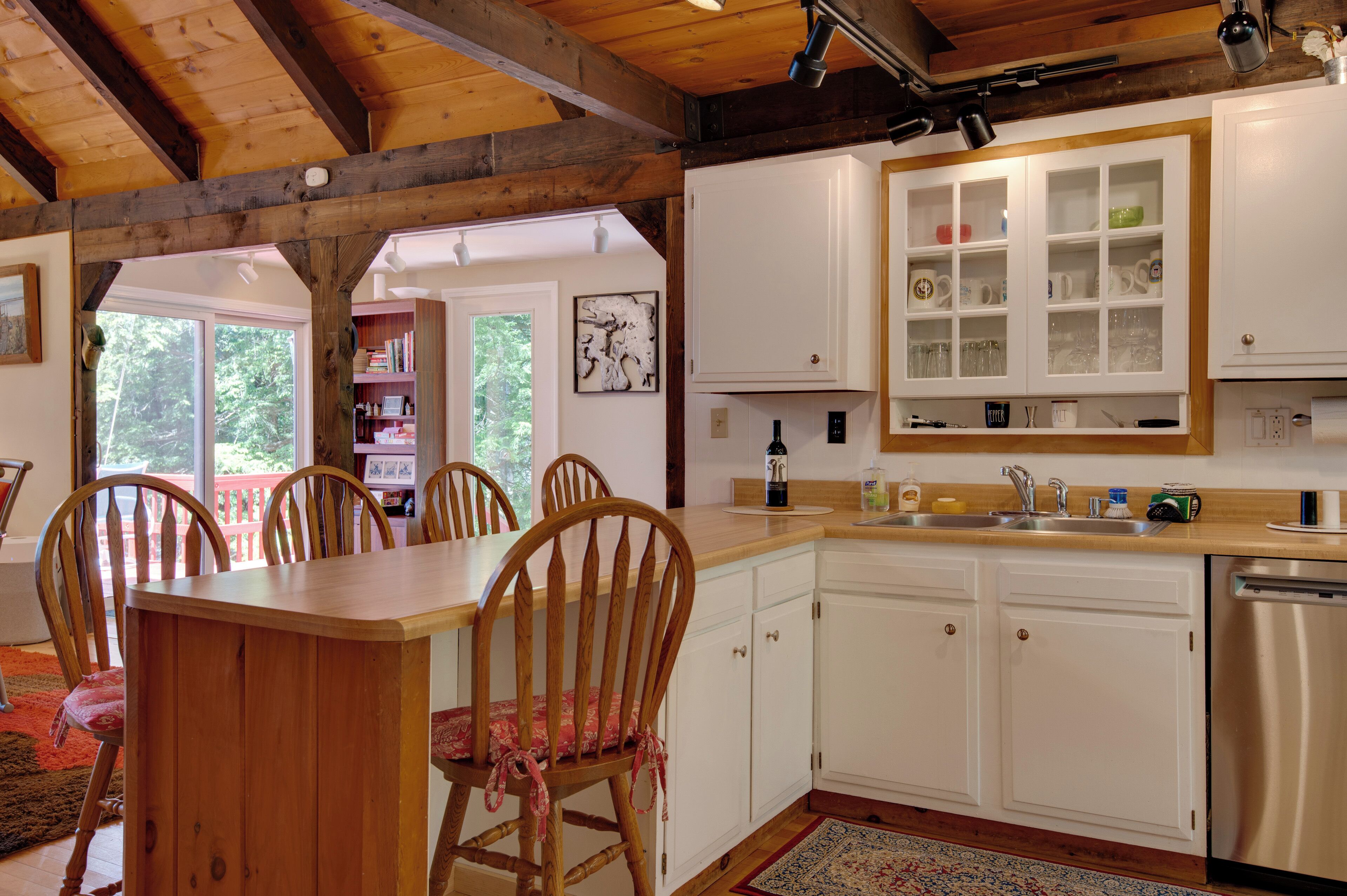 A kitchen with wooden cabinets, a stainless steel dishwasher, and a dining area with wooden chairs and a table.