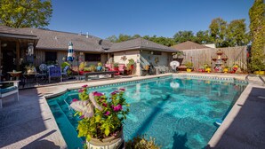 A backyard with a swimming pool, patio furniture, and a wooden fence. - Spacious Bryan Vacation Rental w/ Pool & Patio! (Bryan)