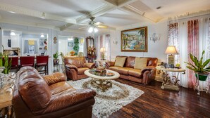 A spacious living room with leather sofas, a coffee table, and a dining area with a chandelier. - Spacious Bryan Vacation Rental w/ Pool & Patio! (Bryan)