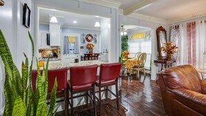 A spacious living room with a brown leather sofa, a dining area with red chairs, and a kitchen in the background. - Spacious Bryan Vacation Rental w/ Pool & Patio! (Bryan)