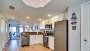 Une cuisine moderne avec des armoires blanches, des appareils en acier inoxydable et un plancher en bois.