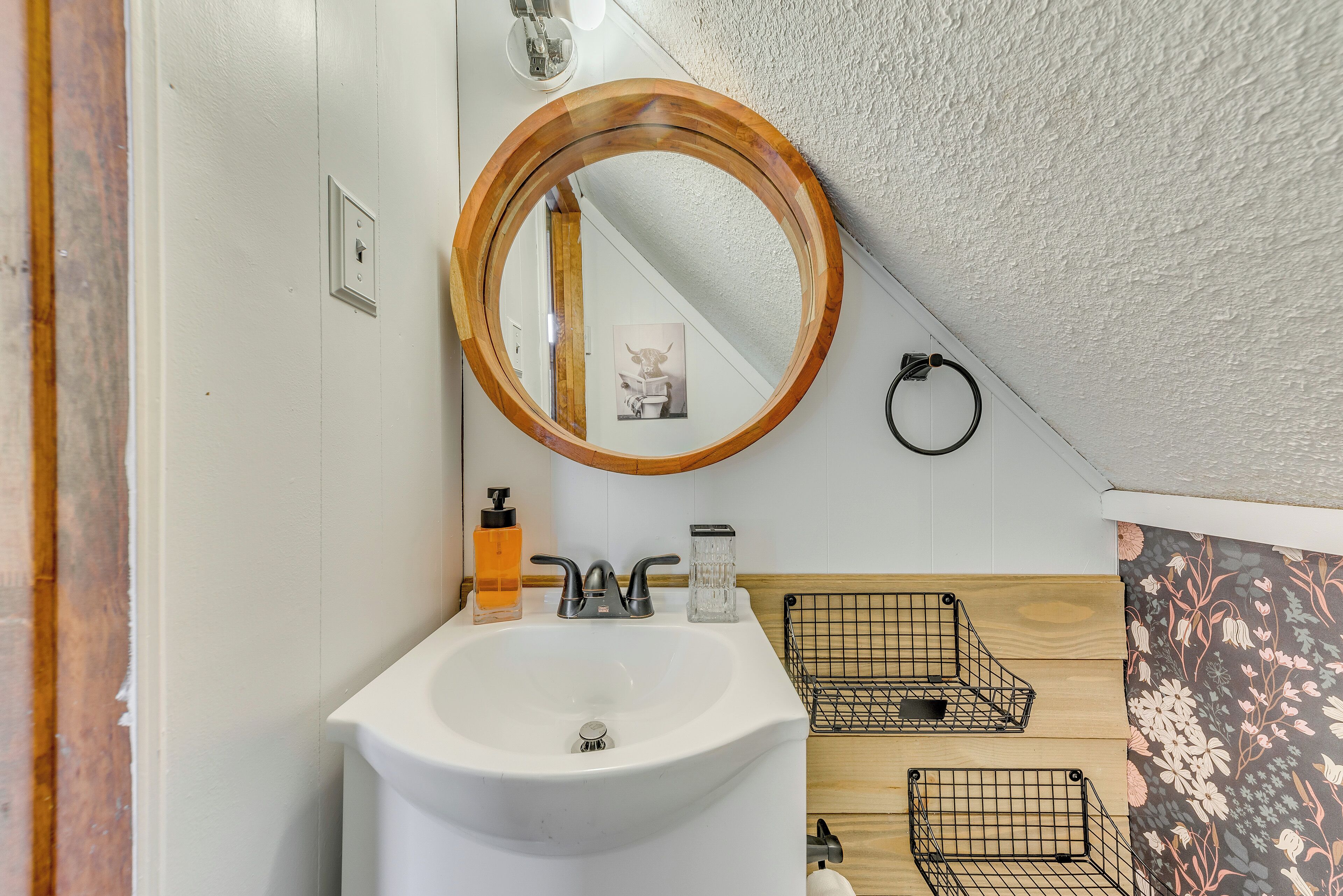 A bathroom with a white sink, a wooden-framed mirror, and a wooden wall panel.