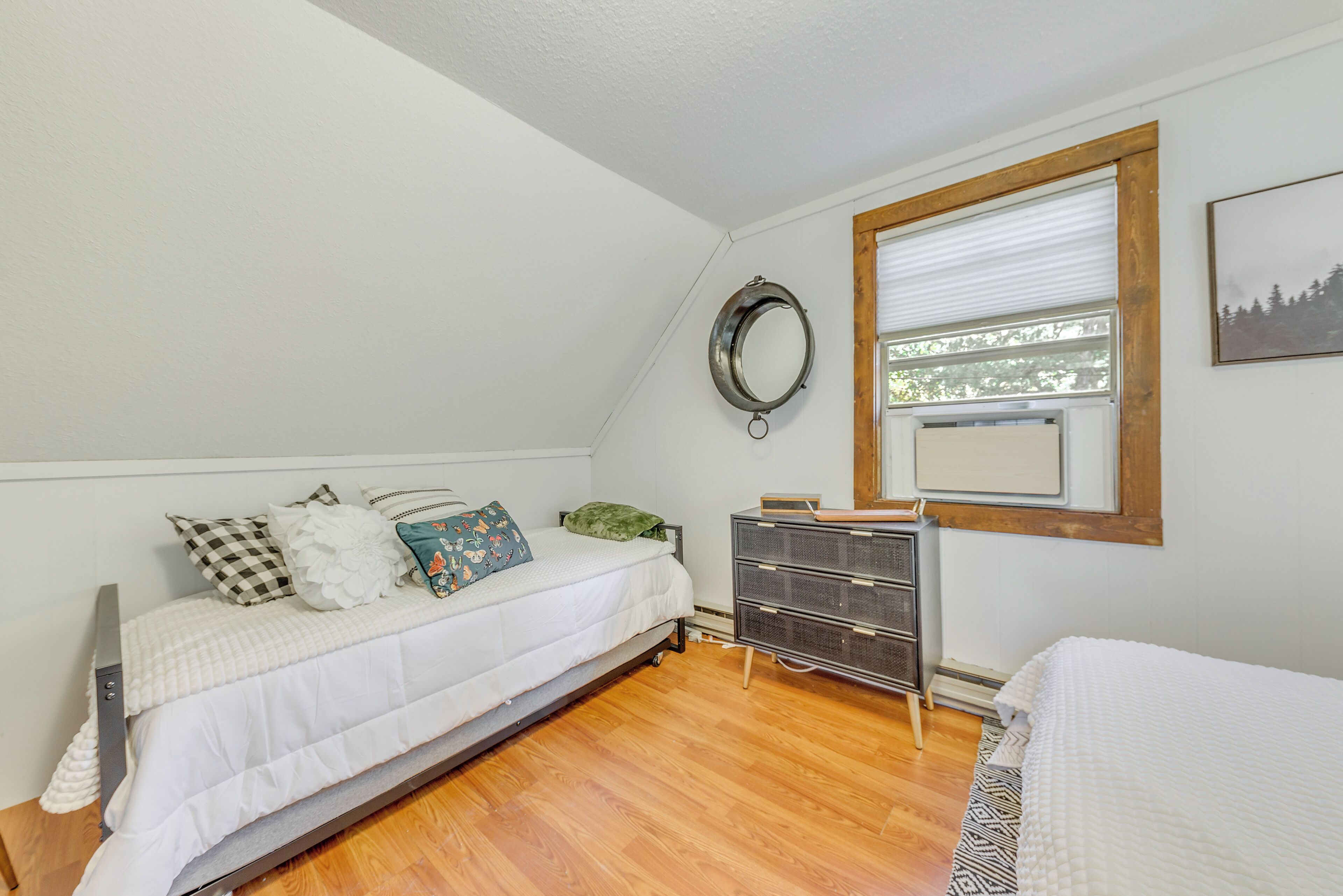 A bedroom with a bed, a dresser, a mirror, and a window.