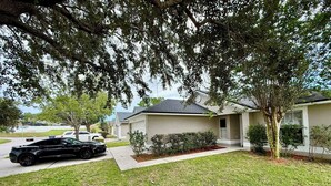 A residential area with a house featuring a garage, a driveway, and a lawn. - Grand Luxury Pines 3BR Pool Home near Disney (Davenport)