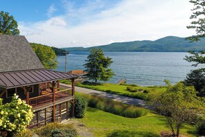 Een vakantiehuis aan het meer met een terras, een pad van stenen en uitzicht op het meer en de bergen.