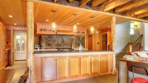 A spacious kitchen with wooden cabinets, a stone backsplash, and pendant lighting. - Serene Silver Bay Home on Lake George w/ Boat Slip (Silver Bay)