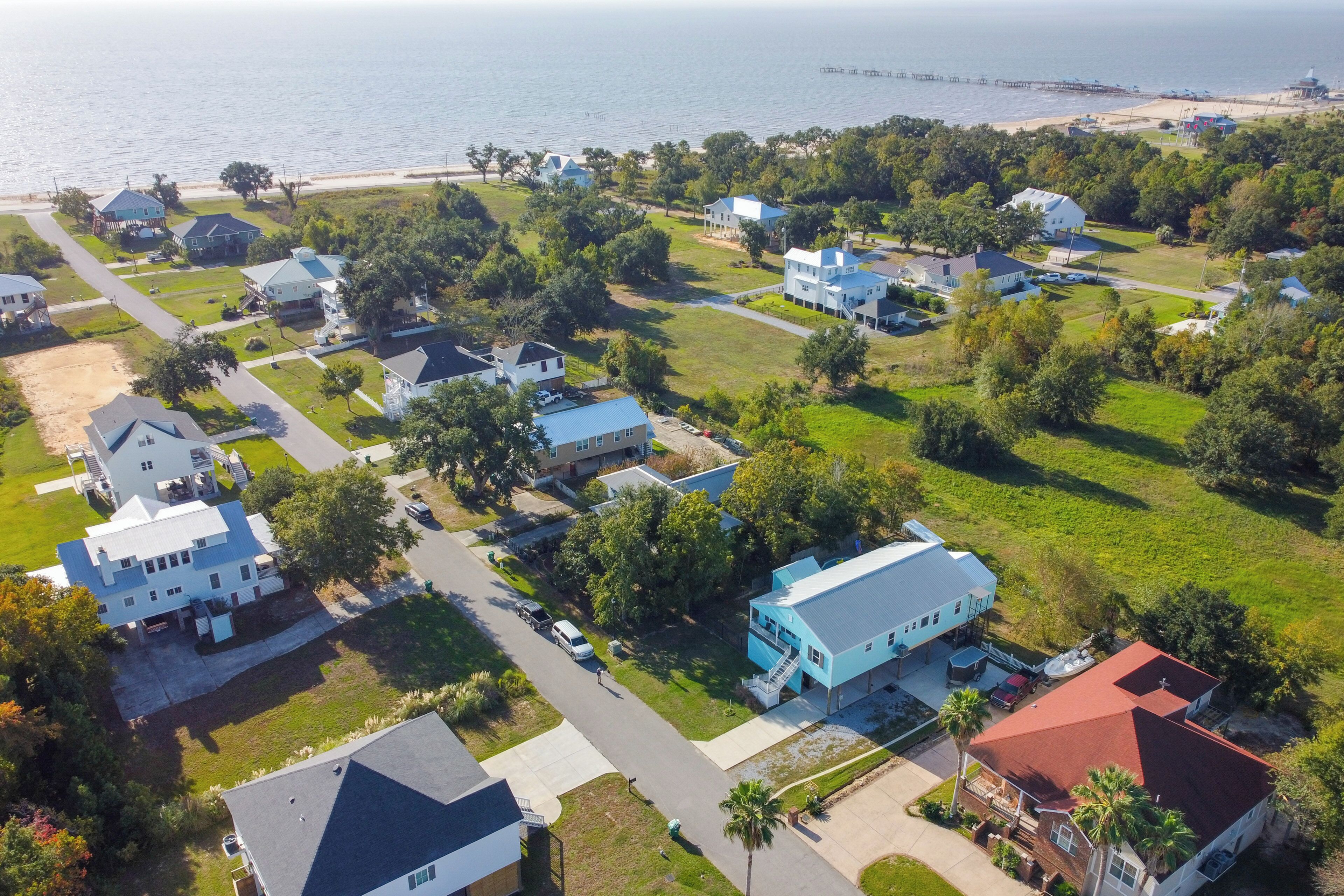 Vista aérea de una zona residencial con casas, calles y una playa al fondo.