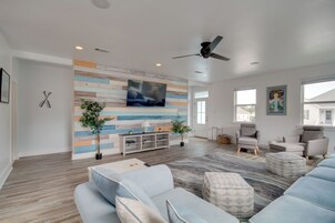 Una sala de estar moderna con un televisor grande, asientos cómodos y un detalle decorativo en la pared.