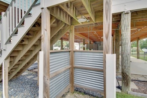 A wooden staircase leading to a covered outdoor area with a metal roof and a corrugated metal wall.