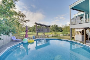 A swimming pool with a wooden deck, a slide, and a fenced area with lounge chairs. - Sunny Waveland Home Rental w/ Pool: Walk to Beach! (Waveland)