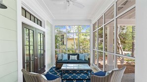 A covered porch with wicker furniture, a glass table, and a view of the outdoors. - WaterColor! Steps to Seaside, WC Tennis! LSV/Golf Cart & 2 Bikes Included! Secluded but Central! (Santa Rosa Beach)