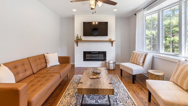 Ein Wohnzimmer mit einem braunen Ledersofa, einem weißen Sofa, einem Holztisch und einem Kamin.
