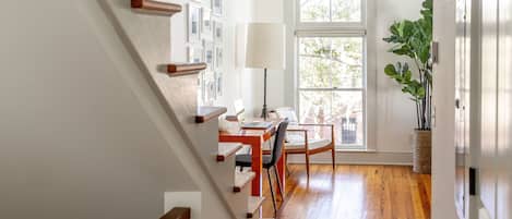 A staircase with wooden handrails leading to a dining area with a table, chairs, and a lamp.