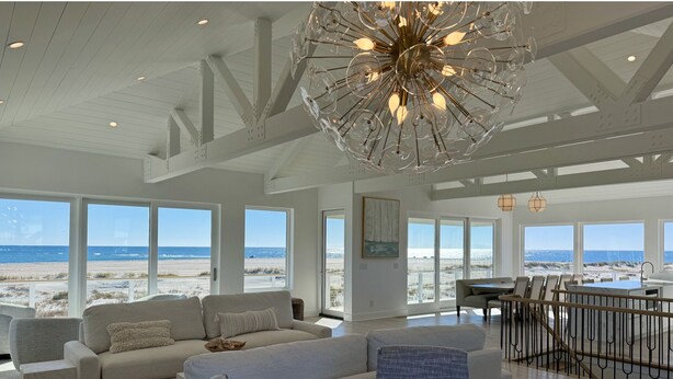 A spacious living room with a large sectional sofa, a dining area with a bar, and large windows offering a view of the beach. - Oceanfront 10 bdrm w/Pool/Elevator on The Point. Best Views on the Island! (Emerald Isle)