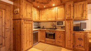 Una cucina in legno con elettrodomestici integrati, tra cui piano cottura, microonde e forno.