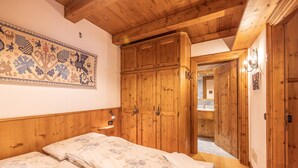 Una stanza in legno con un letto, un armadio in legno e un ingresso che conduce al bagno.