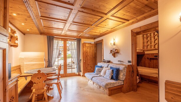 Una stanza con pavimento in legno, un divano, una scrivania in legno e un letto con testiera in legno.