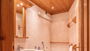 Un bagno con rivestimento in legno, una vasca da bagno grande, un doppio lavandino e un water.