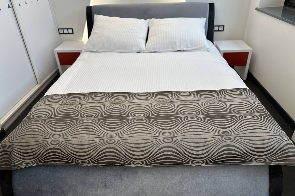 Un lit bien fait, avec une couvre-lit à rayures et un plaid à motifs.