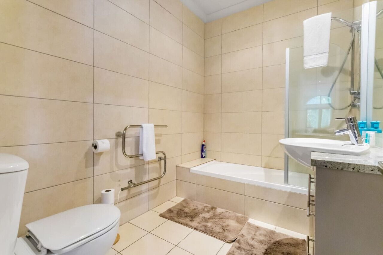 Een badkamer met toilet, douche, wastafel en bad.