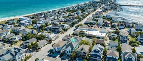 An aerial view of a coastal residential area with houses, a beach, and a marina.