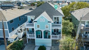 A multi-story house with a balcony on the second floor, a covered front porch, and a fenced yard. - Beach Lovers' Paradise: Beach, Pier, and Dining Nearby! (Wrightsville Beach)