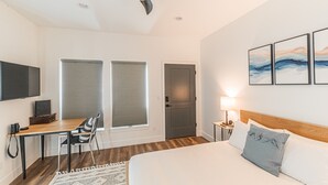 Une chambre d’hôtel moderne, équipée d’un lit, d’un bureau, d’une chaise et d’une œuvre d’art au mur.