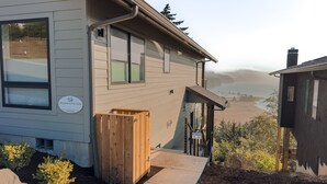 Une propriété située en bord de mer, dotée d’une terrasse en bois, offrant une vue sur l’océan et d’un panneau indiquant qu’il s’agit d’une location de vacances pour profiter de la plage.