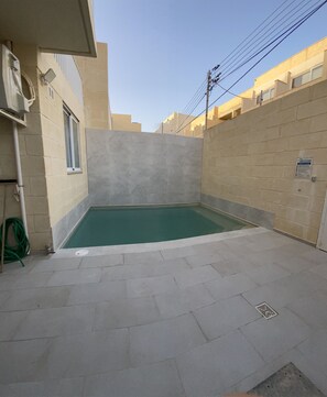 A small, rectangular swimming pool with a tiled deck, surrounded by walls and a window. - AXARA Modern Self-Catering Holiday House in Xaghra (Xaghra)