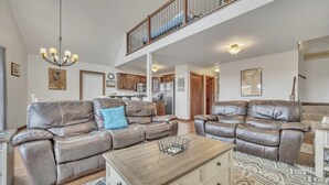 Ein großzügiges Wohnzimmer mit Ledersofas, einem Holztisch und einer hohen Decke mit Balkon.