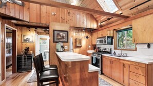 A wooden cabin interior with a kitchen, bar area, and dining space. - Mountain Memories - river access, pet friendly w/ hot tub (Baring)