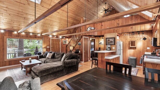 A spacious wooden cabin with a large living area, a kitchen, and a dining table. - Mountain Memories - river access, pet friendly w/ hot tub (Baring)