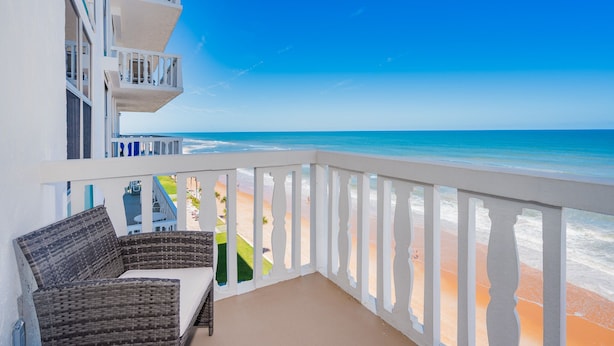 A balcony with wicker furniture and a view of the beach.