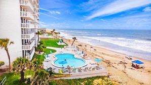 A hotel with a pool, beach, and ocean view.