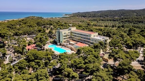 An aerial view of a resort with a large swimming pool, multiple buildings, and a backdrop of a coastal landscape. - Paglianza (Peschici)