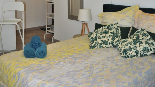 Un dormitorio ordenado con cama, una silla, un escritorio y un espejo.