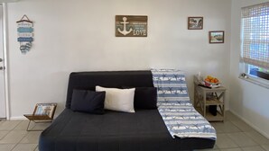 Une chambre avec un lit, une petite table sur laquelle se trouvent des fruits, et une fenêtre donnant sur un beau paysage.