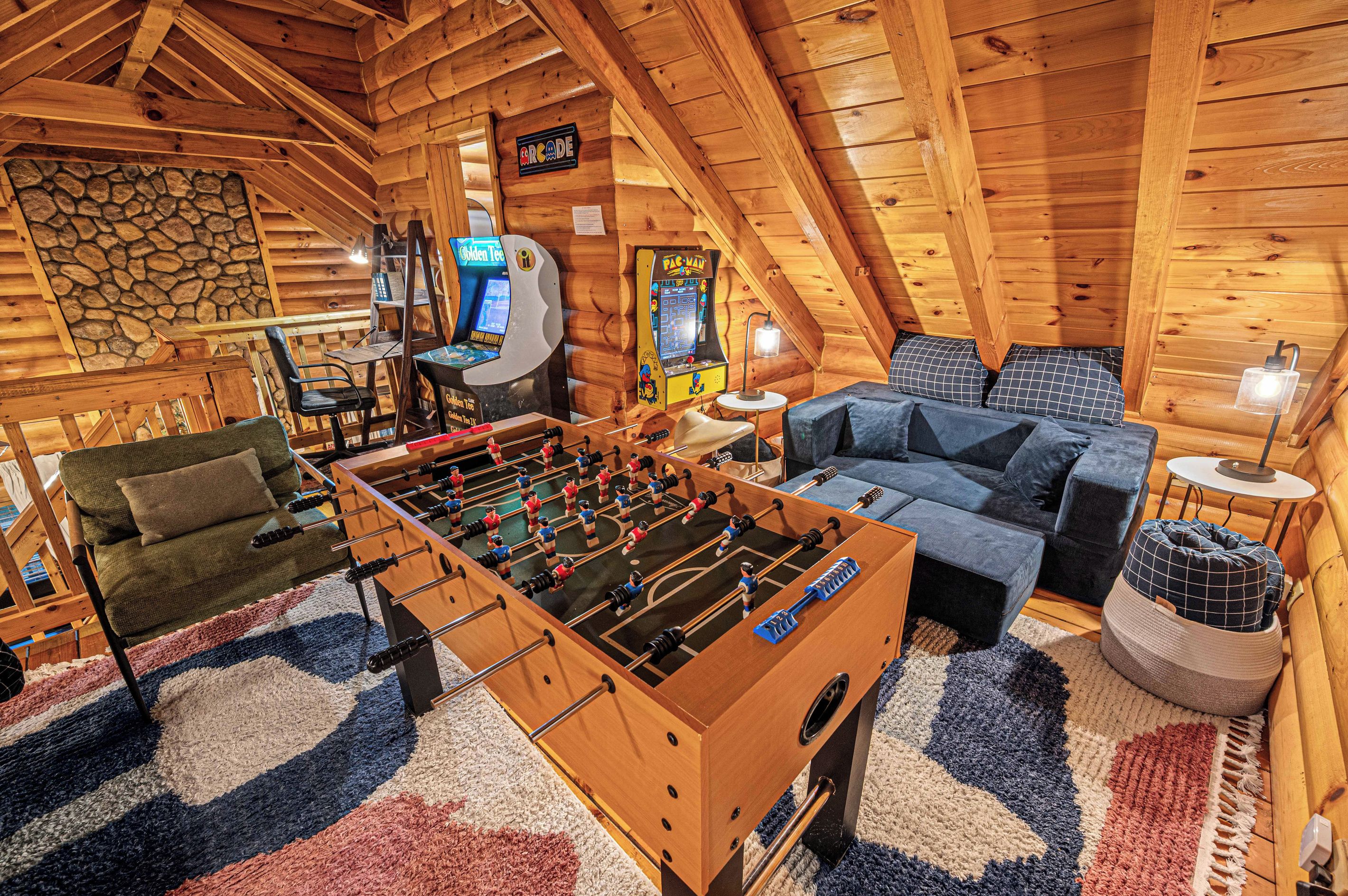 Ein gemütliches Zimmer mit einer Tischfußballplatte, einem Sofa und zwei Spielautomaten.