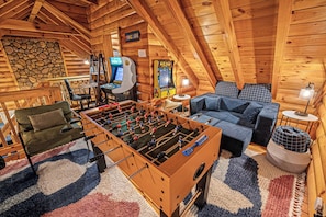 Head up to the arcade loft and claim the foosball table first. Pac-Man and Golden Tee are waiting too — the room the kids won't want to leave and the adults sneak back to after dinner. - Hot Tub · Arcade Loft · Fire Pit · Wooded Cabin (Cherry Log)