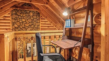 A wooden interior with a stone wall, a desk, and a chair.