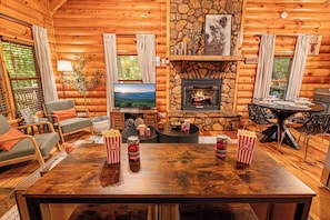 Pull a chair up to the table for popcorn and a movie. Fireplace going, the TV across the room, and the whole group within easy reach of the snacks. - Hot Tub · Arcade Loft · Fire Pit · Wooded Cabin (Cherry Log)