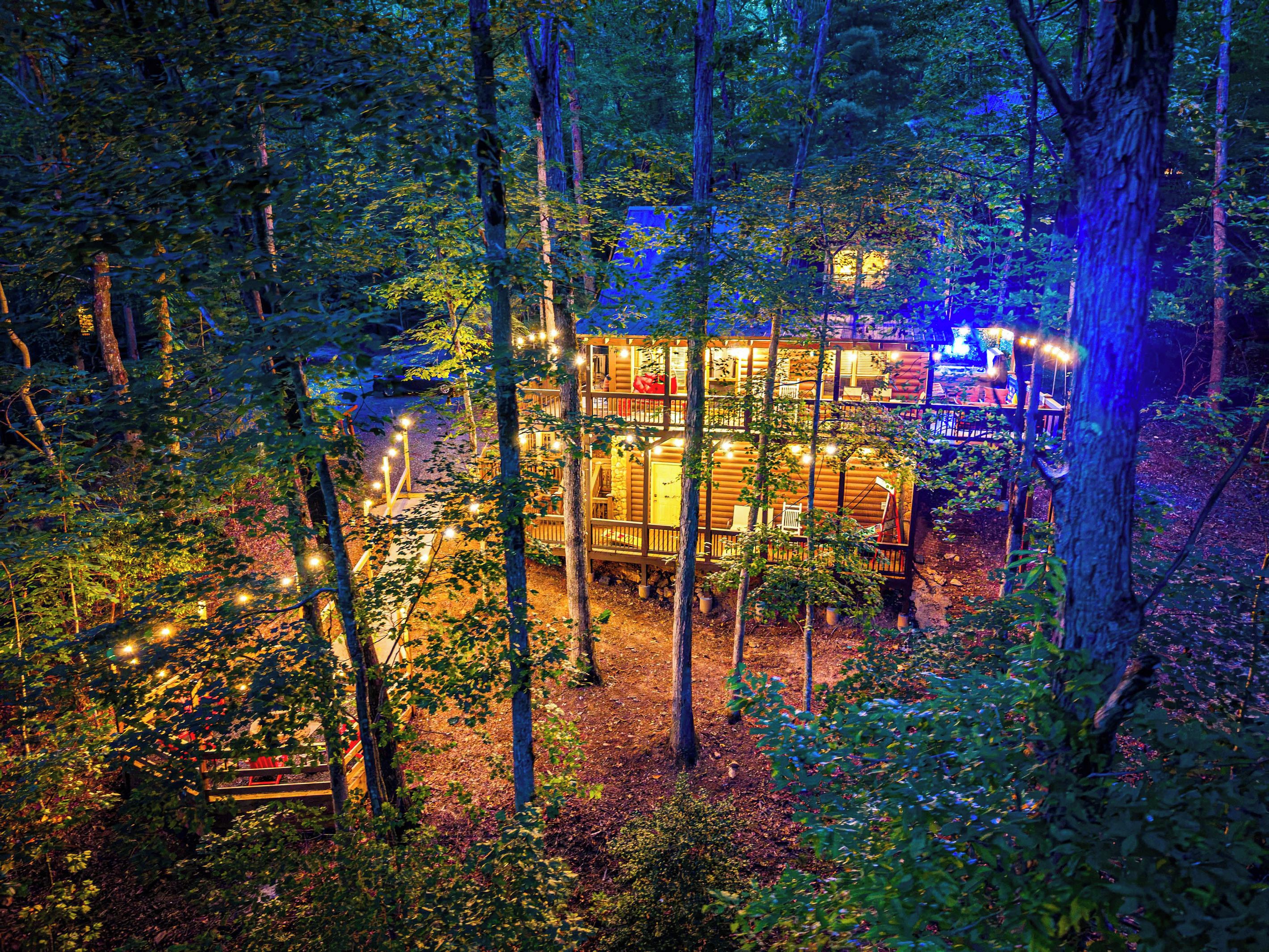 Spot the cabin glowing through the trees after dark. Wooded and secluded, with the deck lights marking the way back from the fire pit.