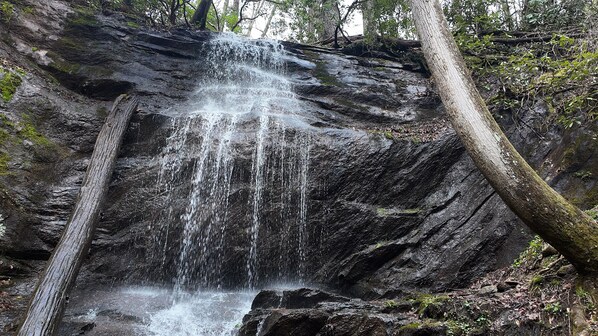 A waterfall cascading down a rocky cliff surrounded by trees. - Hot Tub · Arcade Loft · Fire Pit · Wooded Cabin (Cherry Log)