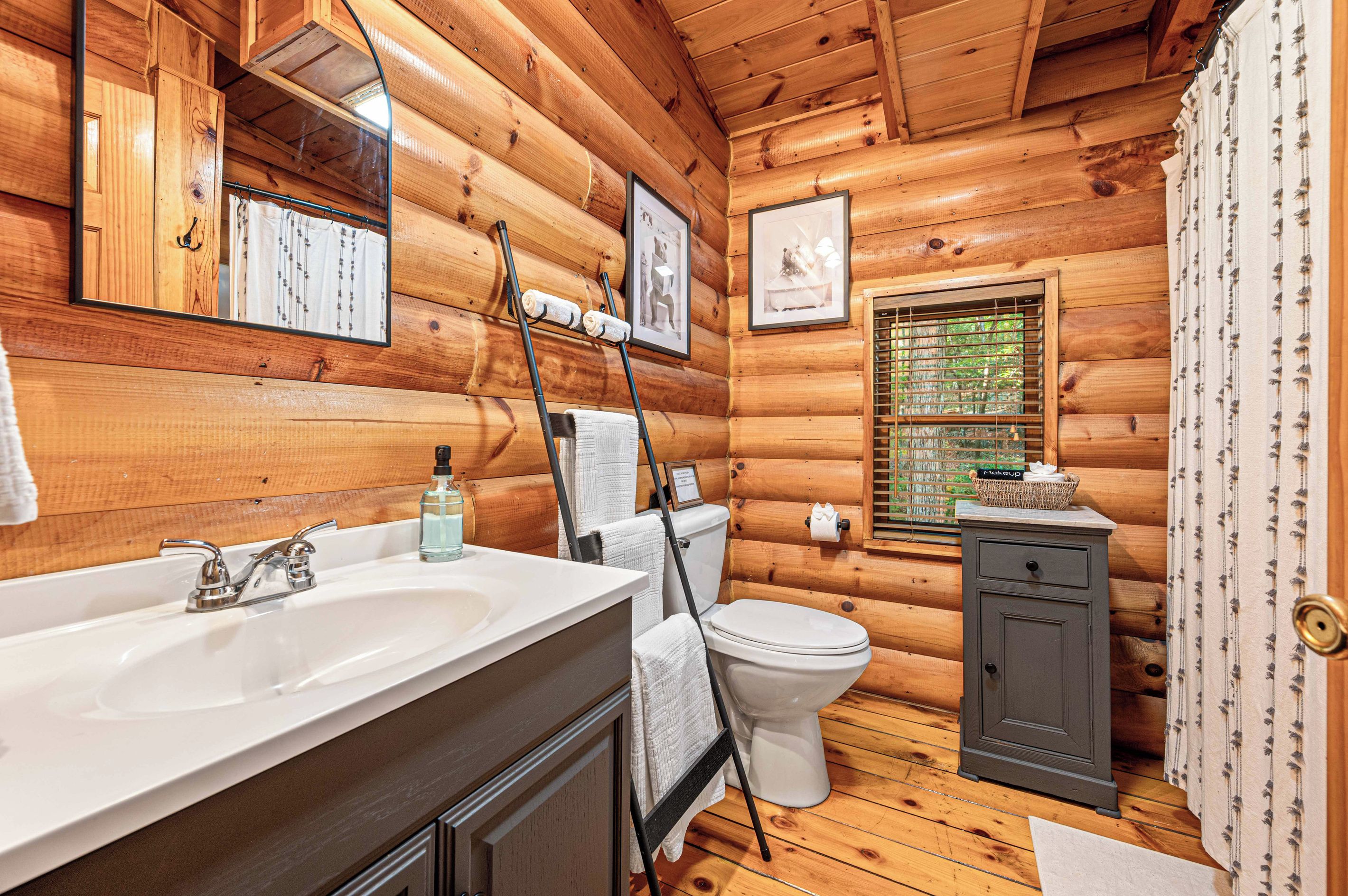 A wooden cabin bathroom with a sink, toilet, and a small cabinet.
